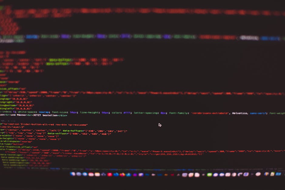 A close-up view of a person's hand typing on a silver laptop keyboard with black keys, placed on a wooden surface. The laptop screen displays lines of code in a dark-themed text editor, with syntax hi
